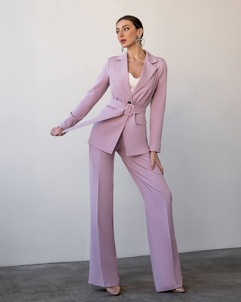 Woman wearing a pink suit with a white top against a plain background