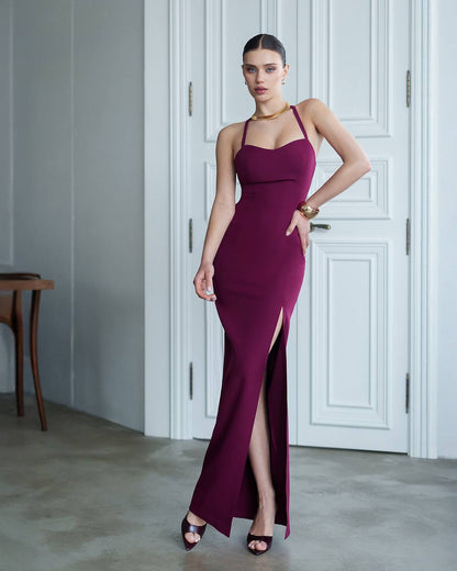 Woman in a burgundy evening gown standing in a room with white paneled walls.