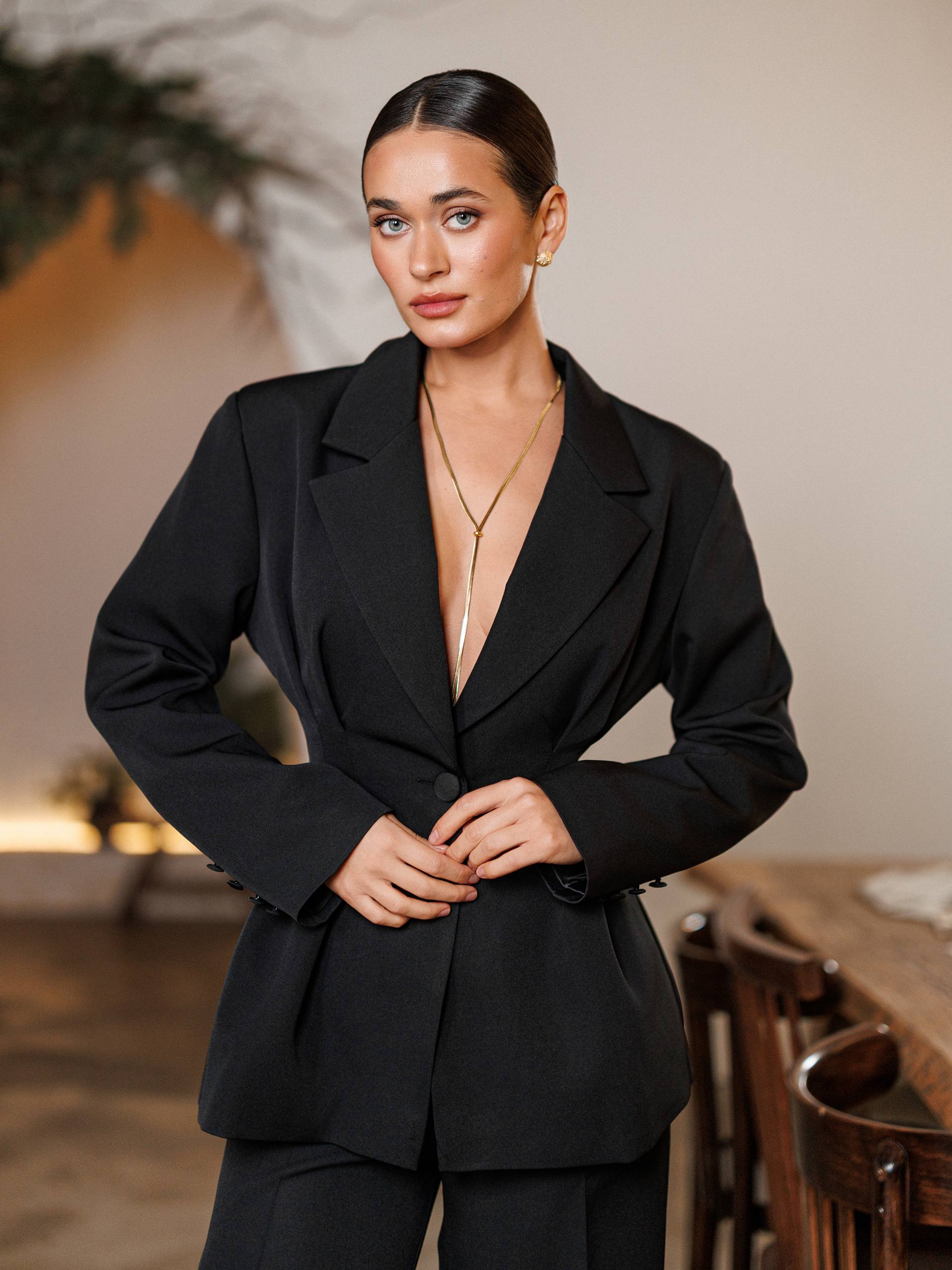 Woman wearing a black suit with a blurred indoor background