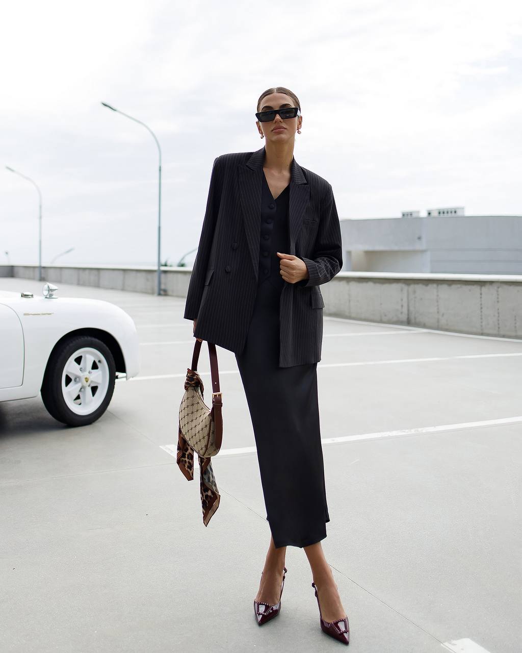 Person wearing a black suit with sunglasses in an urban setting