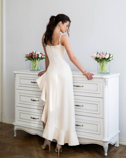 Woman in a white dress standing next to a white dresser with pink flowers on top.