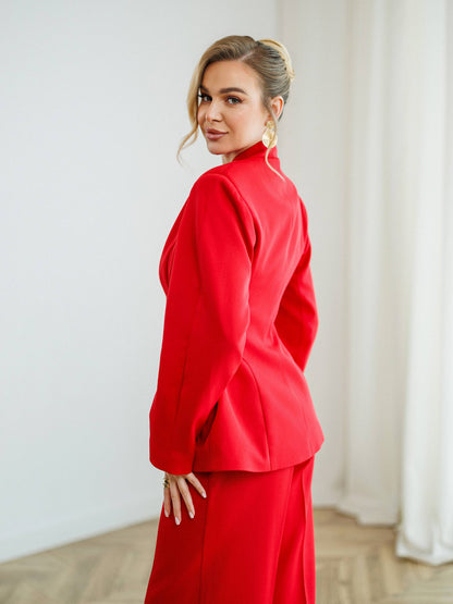 Woman wearing a red outfit standing against a white wall.