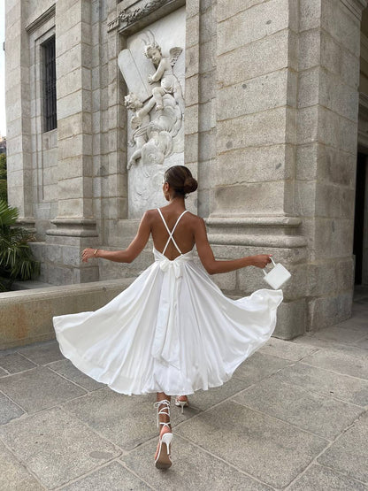 Woman in a white dress standing in front of a stone building with architectural details.