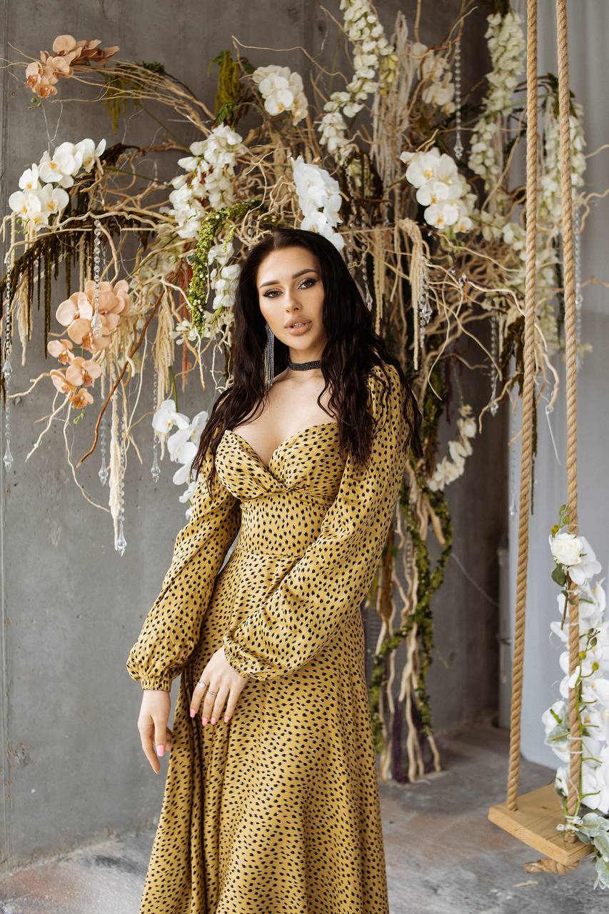 Woman in a gold dress standing in front of floral decorations