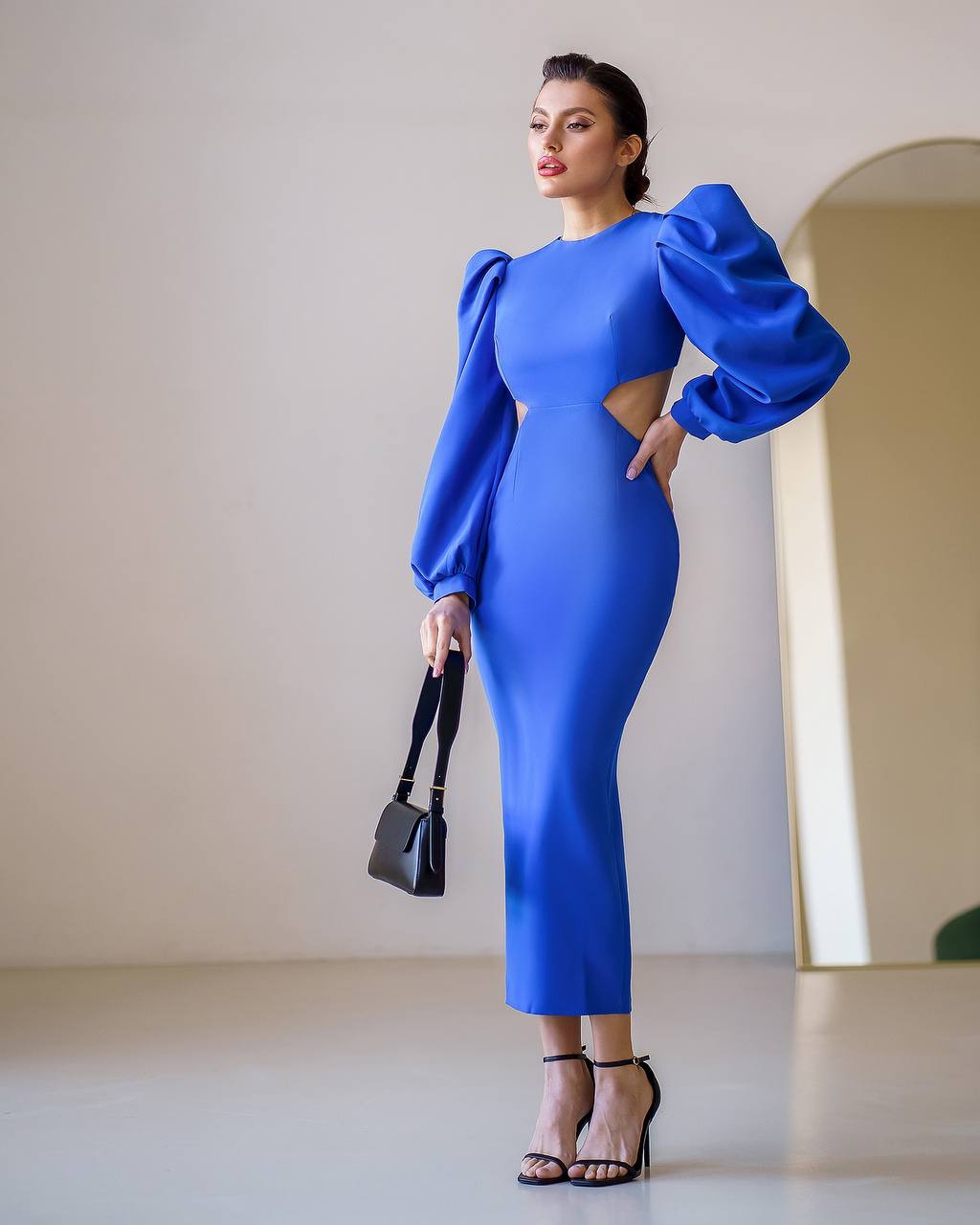 Woman wearing a blue dress with puffed sleeves in a minimalistic setting