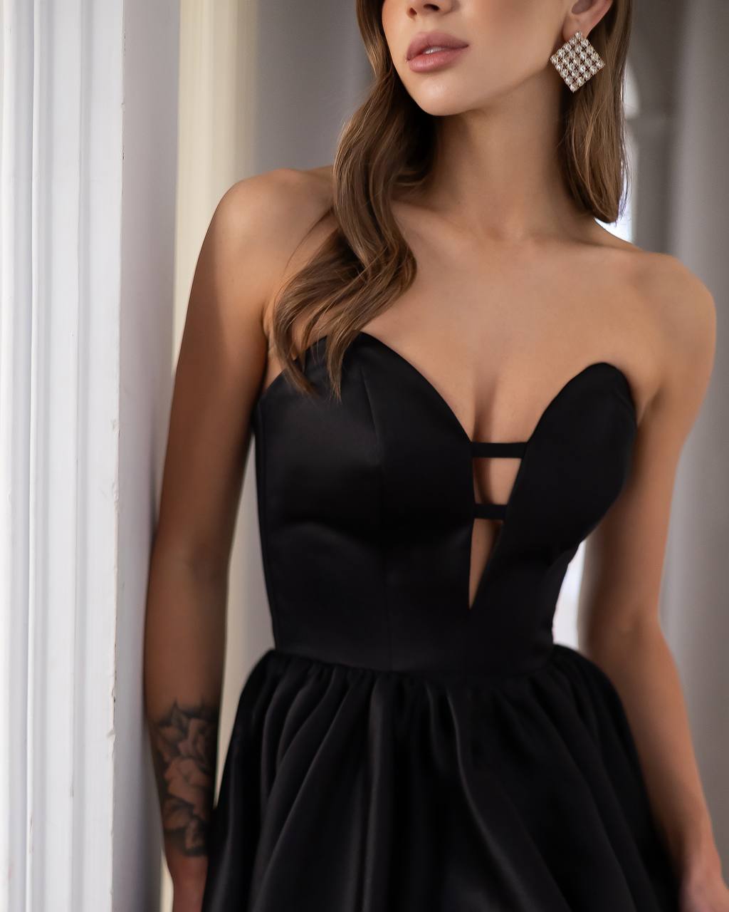 Woman wearing a black strapless dress with a plunging neckline.