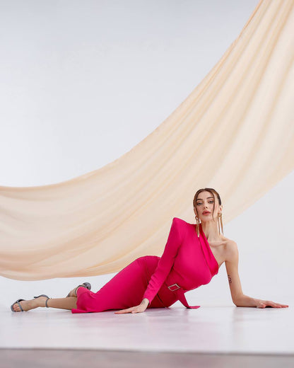 Woman in a bright pink outfit lying on a white floor with a beige curtain in the background