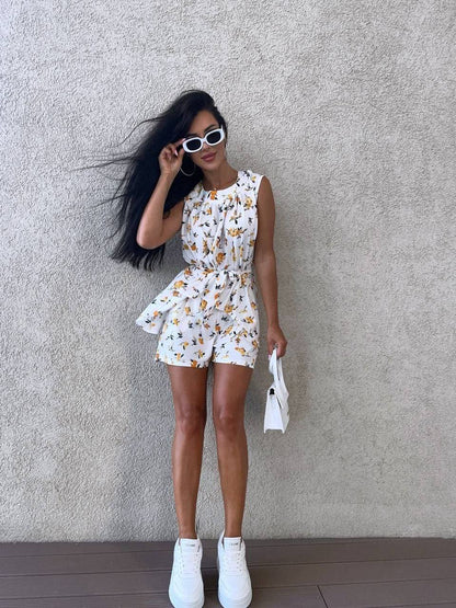 Woman wearing a white floral dress against a gray wall
