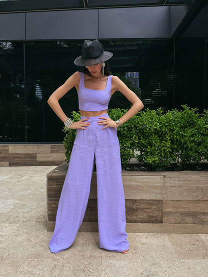 Person wearing a lavender outfit with a hat standing outdoors.