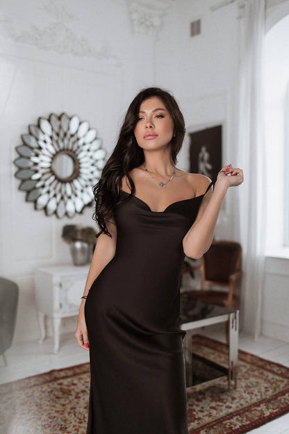 Woman in a black dress standing in a stylish room with decorative elements.