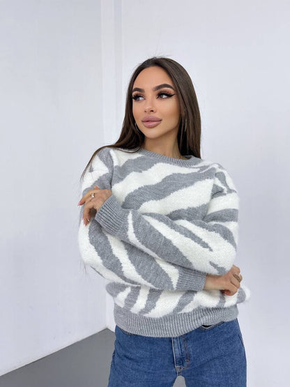 Woman wearing a gray and white patterned sweater against a plain background