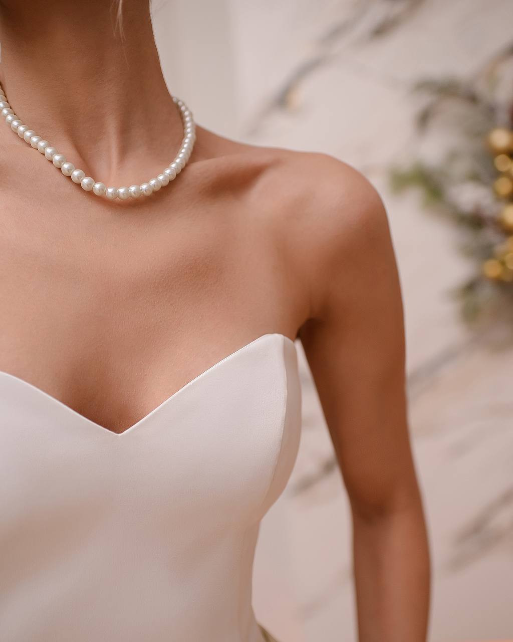 Close-up of a person wearing a pearl necklace with a blurred background