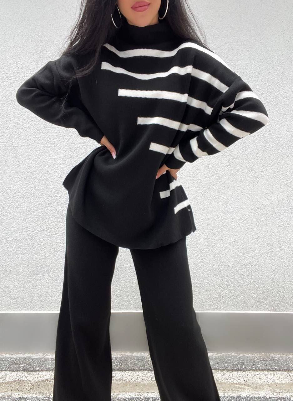 Person wearing a black and white striped sweater with wide-leg pants against a neutral background