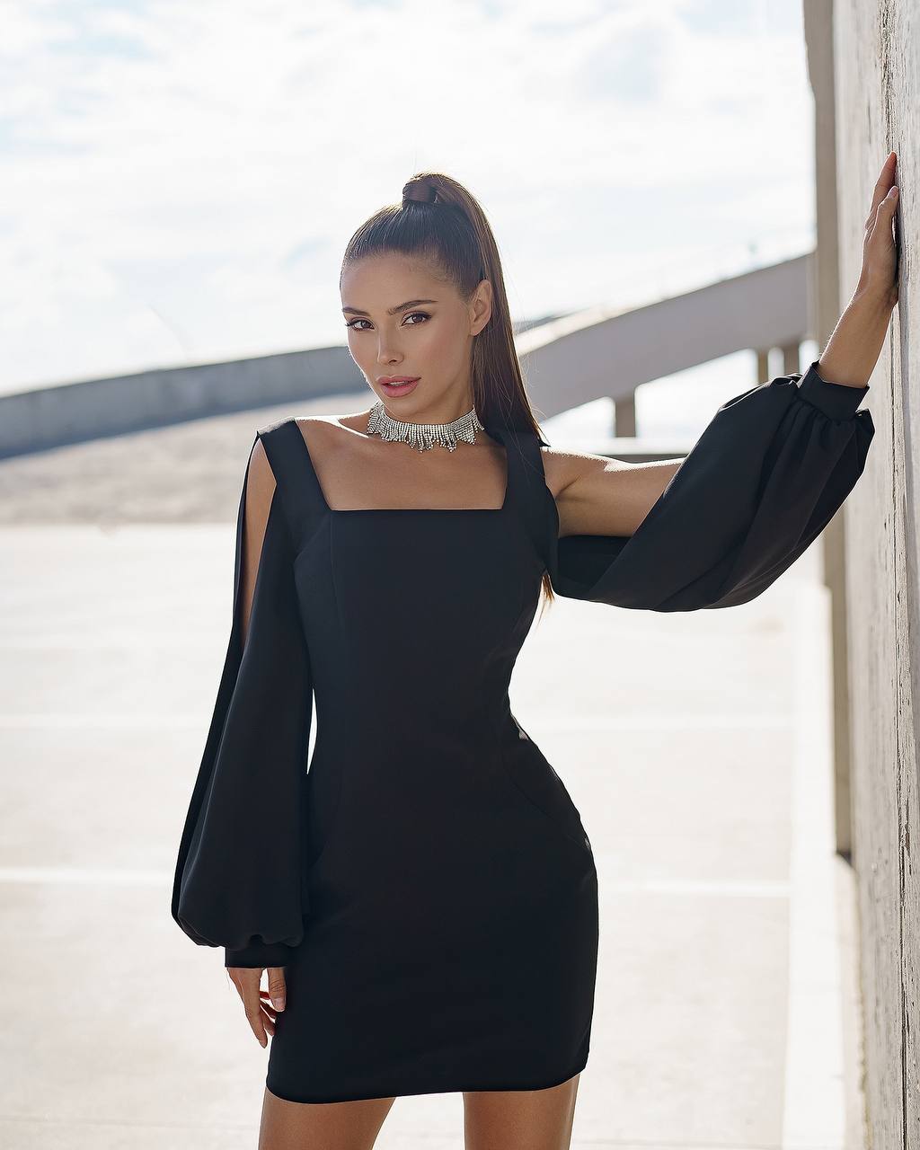 Woman wearing a black dress with puffed sleeves against a light background