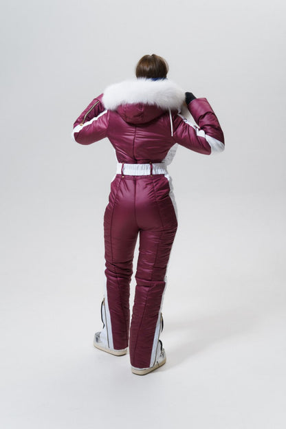 Person wearing a maroon snowsuit with white fur hood on a white background