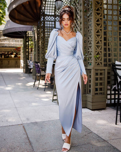Woman in a light blue dress and matching jacket walking outdoors.