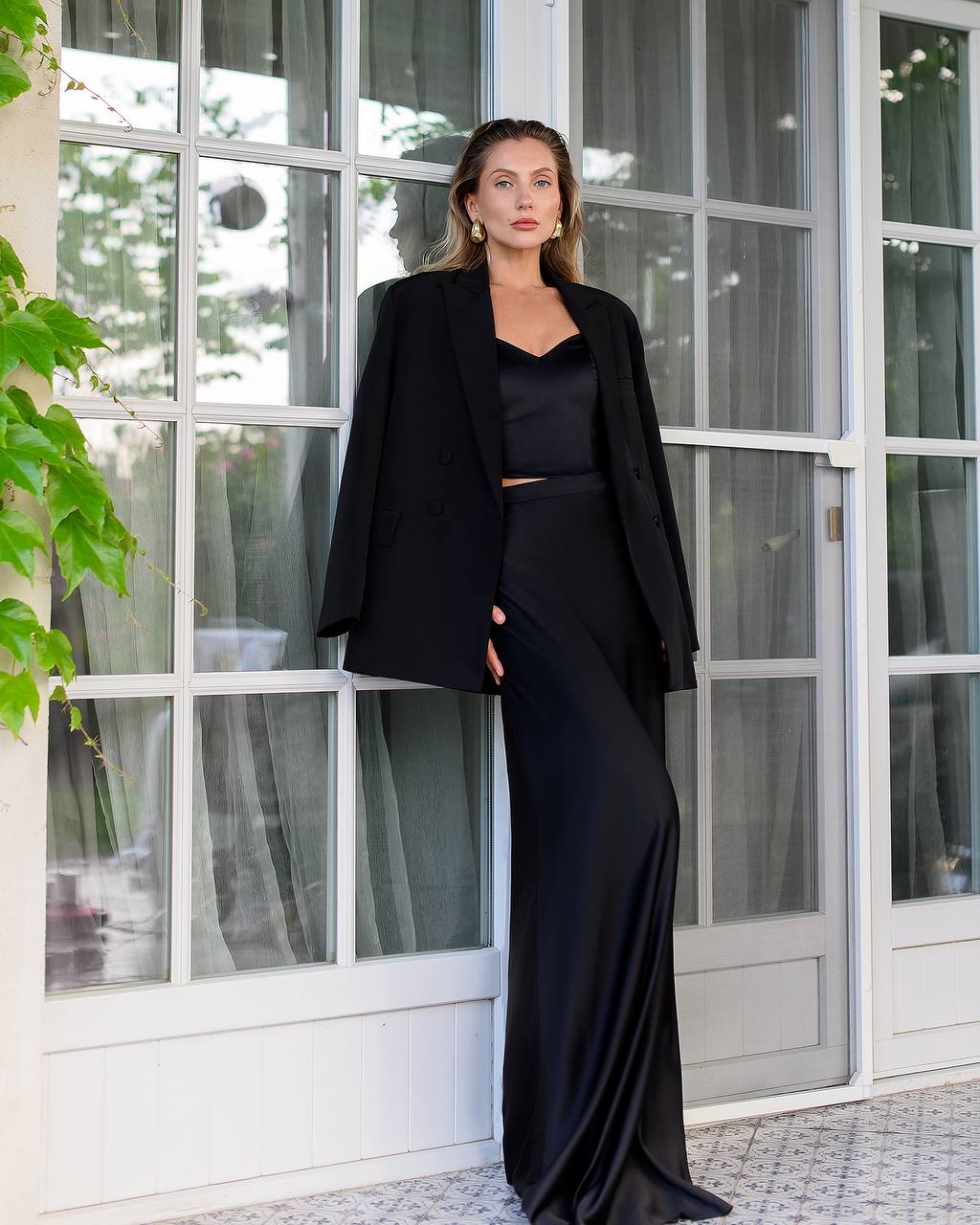 Woman in a black outfit standing in front of a glass door.