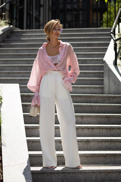 Woman in pink cardigan and white pants standing on outdoor steps