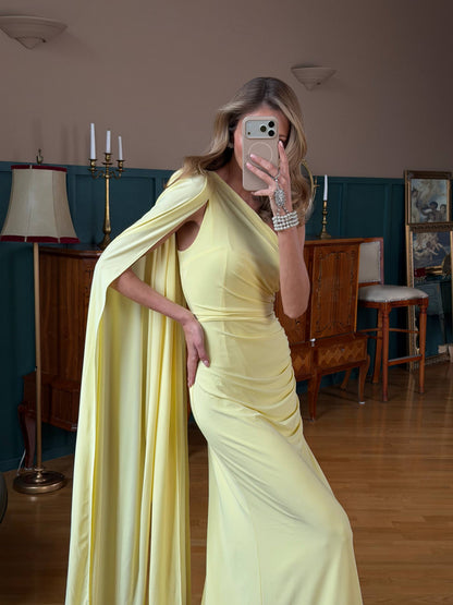 Woman in a yellow dress taking a mirror selfie in an indoor setting.