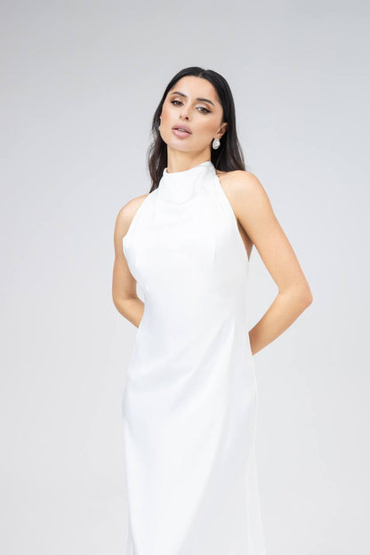 Woman wearing a white sleeveless dress against a plain background