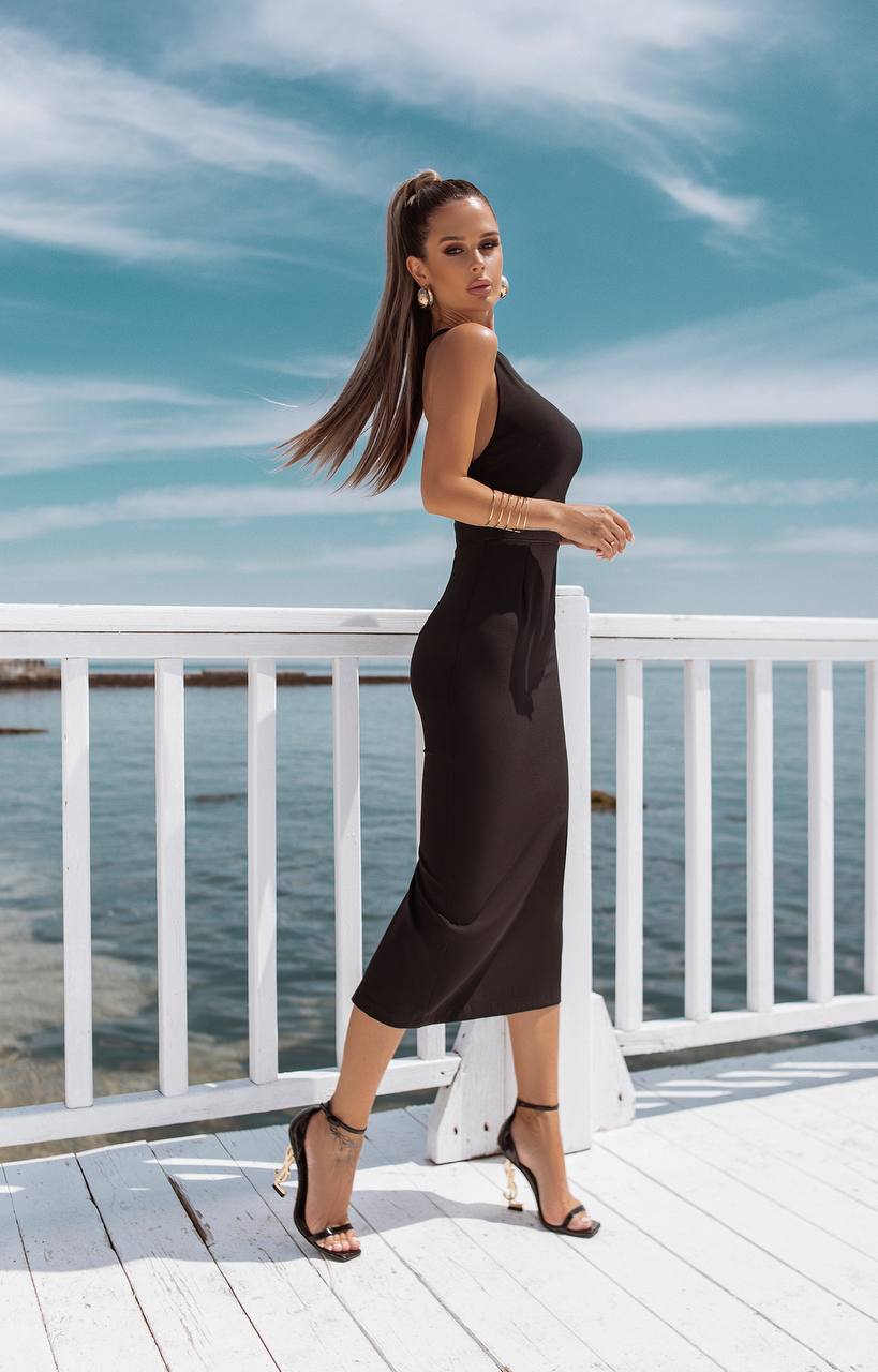 Woman in a black dress standing on a wooden deck by the water