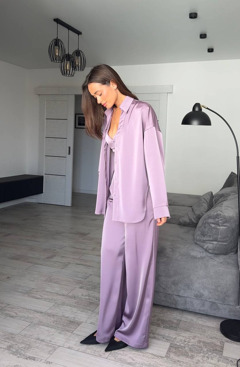 Woman in a lavender pajama set standing in a modern living room.