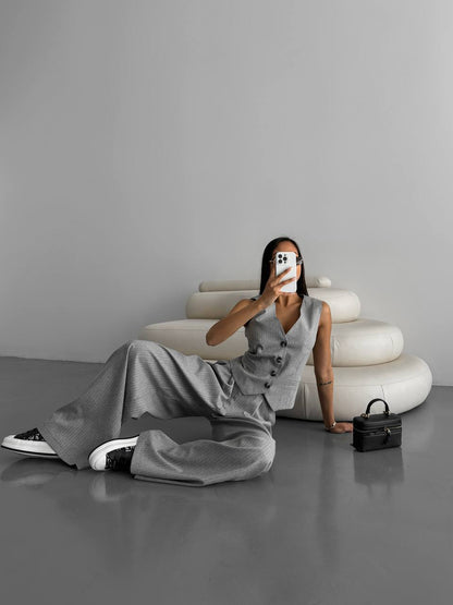 Person taking a selfie in a minimalistic setting with a gray dress and black bag.
