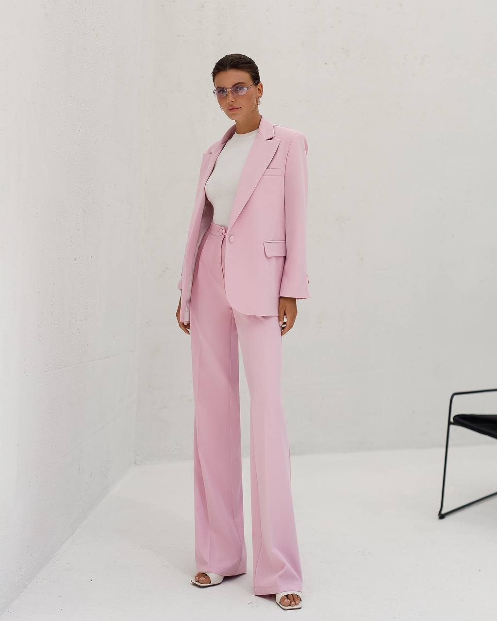 Person wearing a pink suit with a white top against a plain background