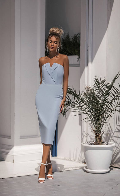 Woman in a light blue strapless dress standing outdoors with a plant in the background