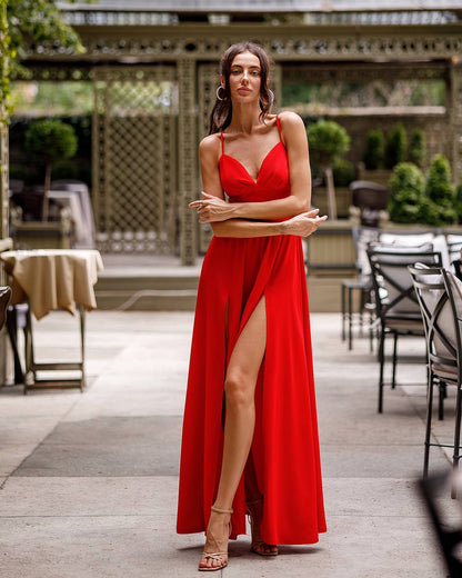 Woman in a red dress standing outdoors with tables and chairs in the background