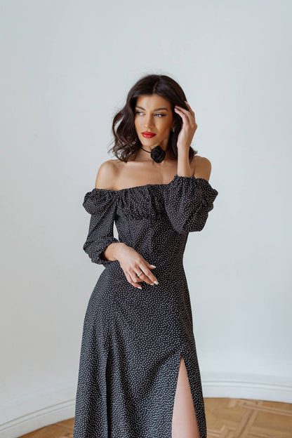 Woman wearing a black polka dot off-shoulder dress with a white background