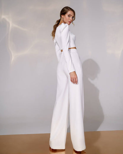 Woman wearing a white outfit with a high collar against a neutral background