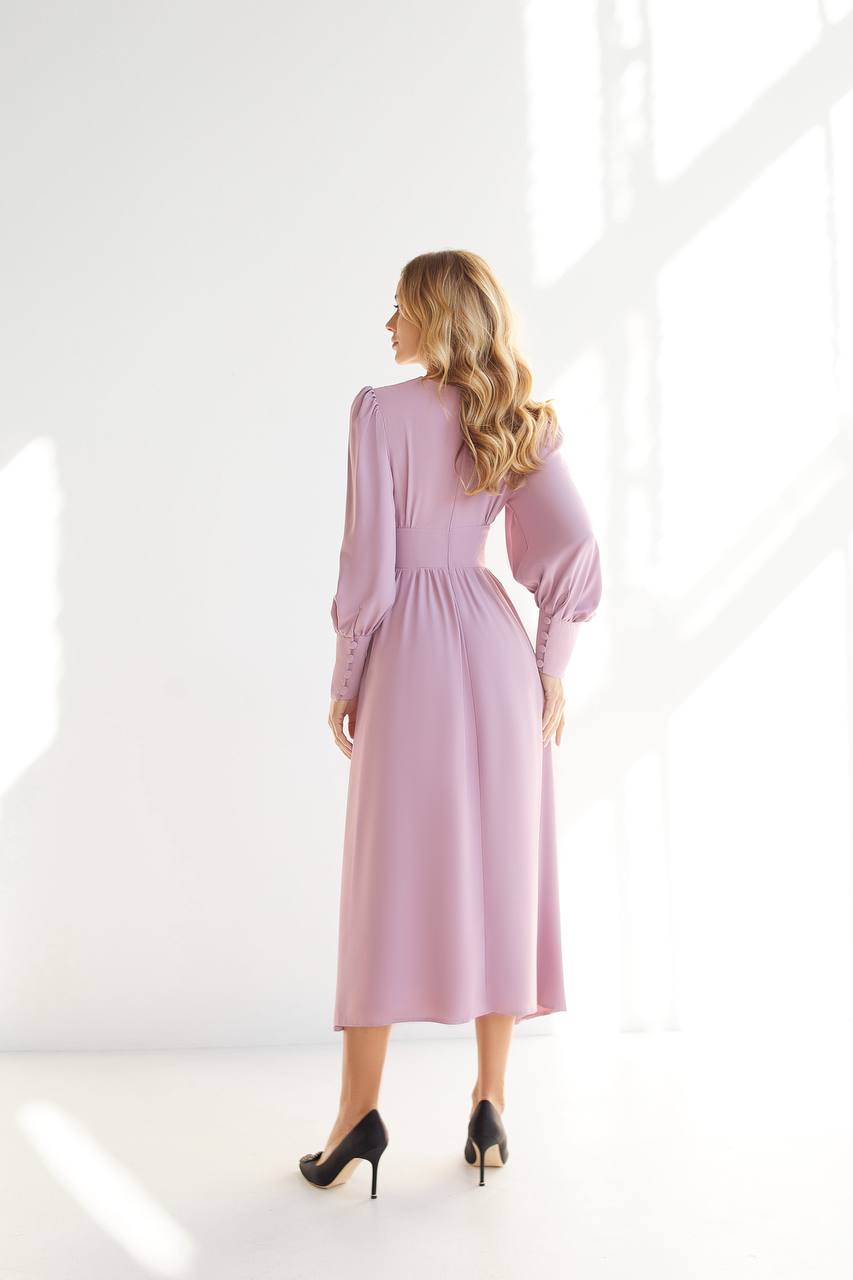 Woman wearing a pink dress standing in a bright room with white walls.