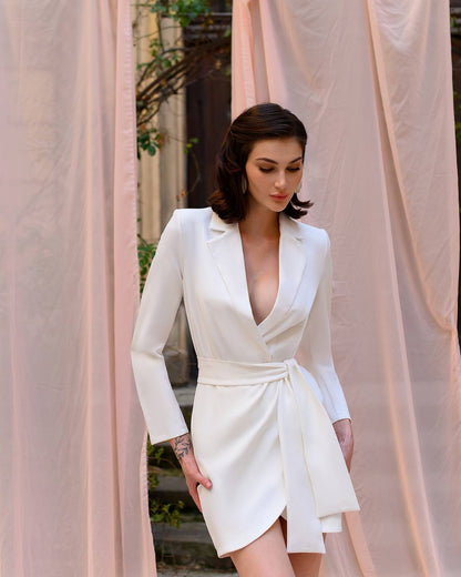 Woman wearing a white dress with long sleeves in front of pink curtains