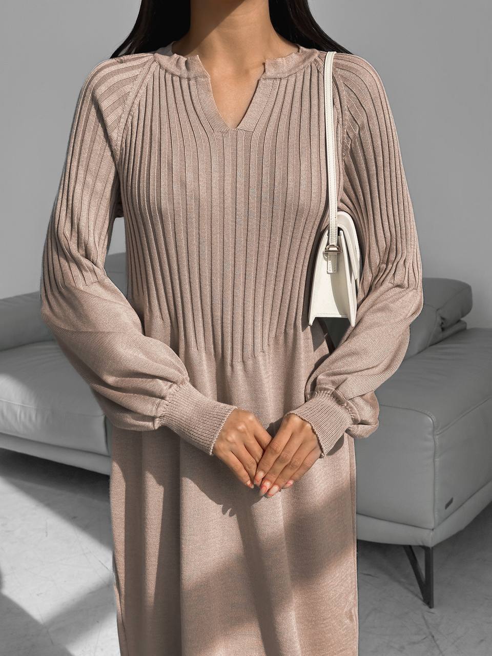 Woman wearing a long ribbed dress in a neutral setting