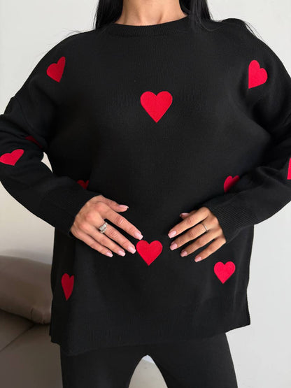 Black sweater with red heart patterns worn by a person.