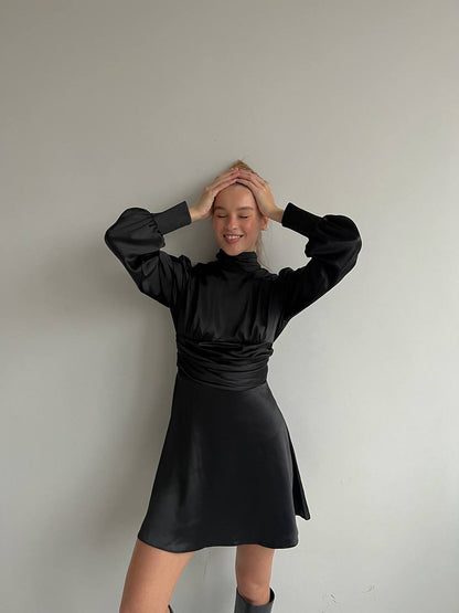 Person wearing a black dress against a plain background