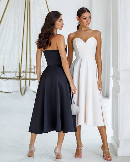 Two women wearing black and white strapless dresses standing side by side.