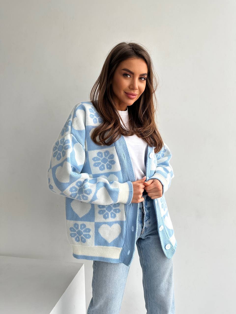 Woman wearing a blue and white patterned cardigan against a plain background