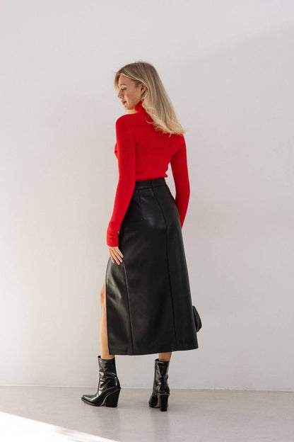 Woman wearing a red sweater and black leather skirt against a white background