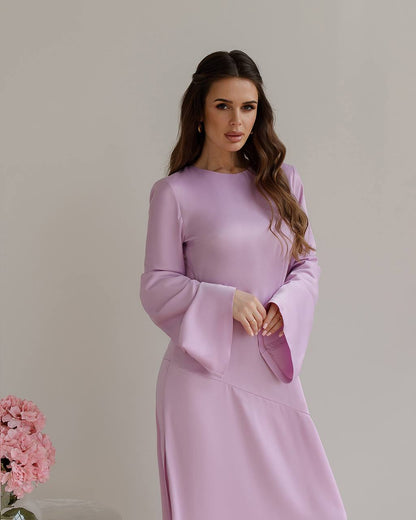 Woman wearing a light purple dress with long sleeves against a plain background
