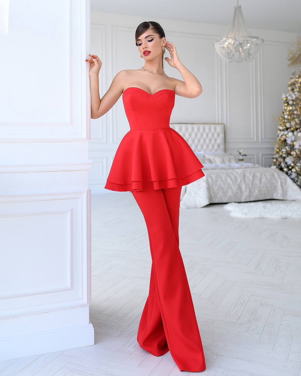 Woman wearing a red strapless dress in a white room with a Christmas tree.