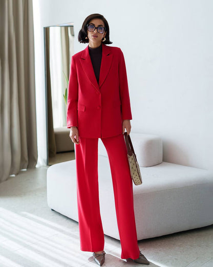 Woman in a red suit standing in a modern room with white furniture.