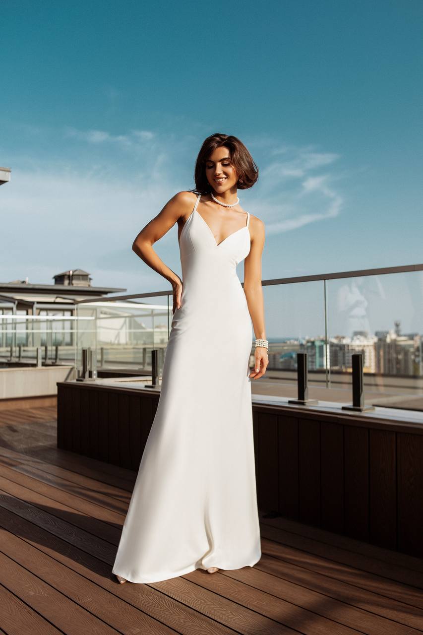 Woman in a white dress standing on a rooftop with a cityscape in the background