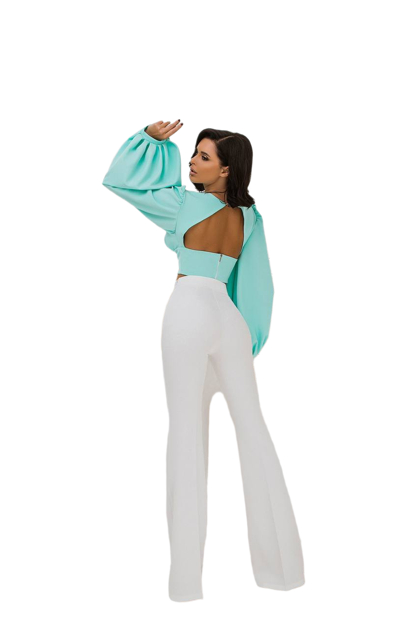 Woman wearing a light blue open-back top and white pants on a white background