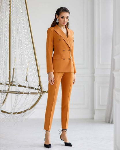 Woman wearing a mustard yellow suit standing in a minimalistic room with decorative elements.