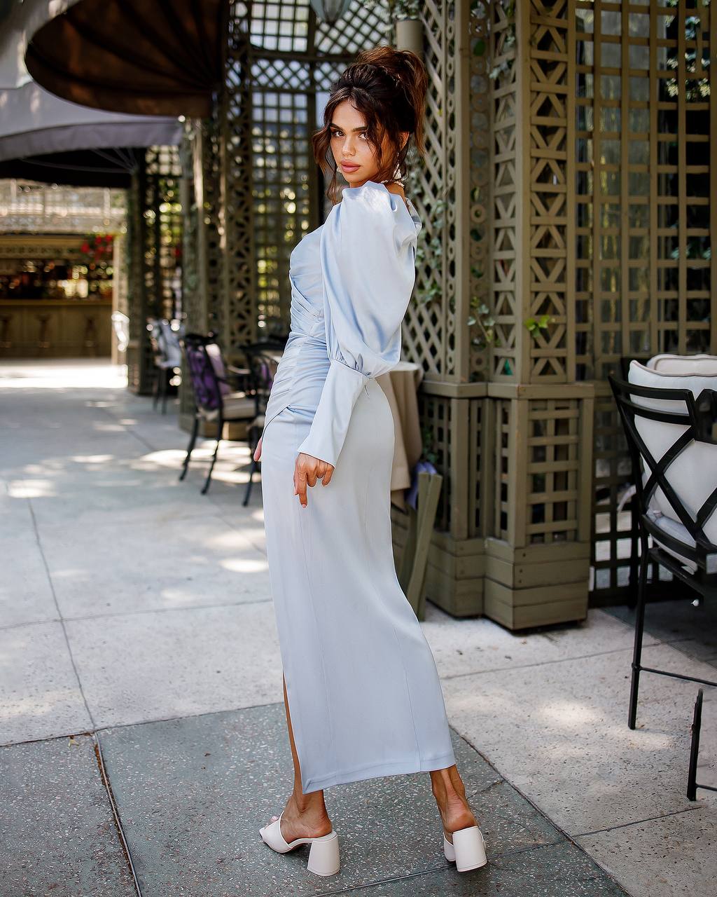 Woman in a light blue dress standing outdoors on a patio.