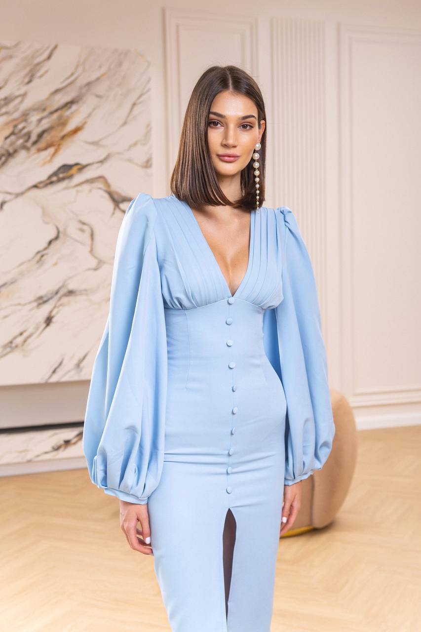 Woman wearing a light blue dress with puffed sleeves in an indoor setting.