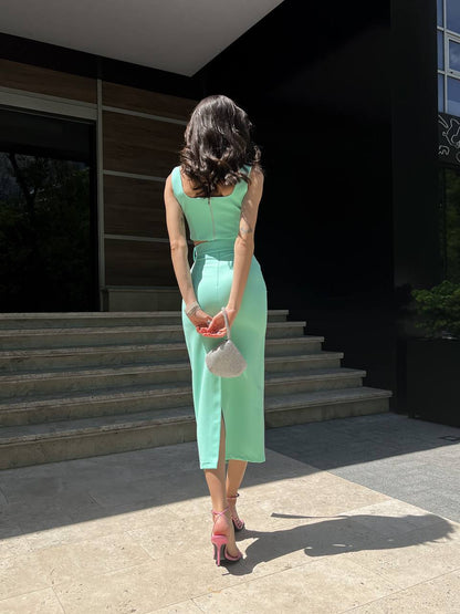 Woman in a light green dress standing on steps outside a building