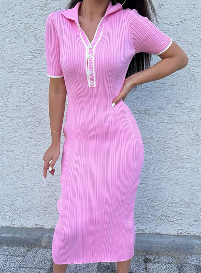 Person wearing a pink ribbed dress against a light gray wall.